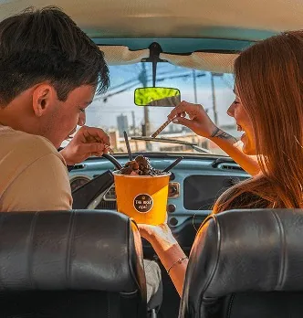 Casal dividindo açaí dentro de um carro antigo