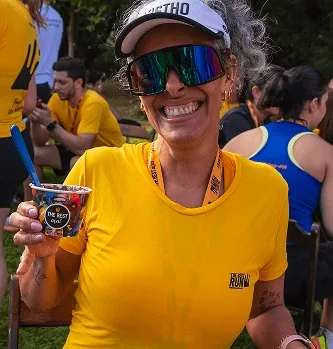 Corredora sorrindo com copo The Best Açaí após prova