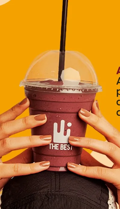 Shake proteico de açaí The Best segurado com as duas mãos